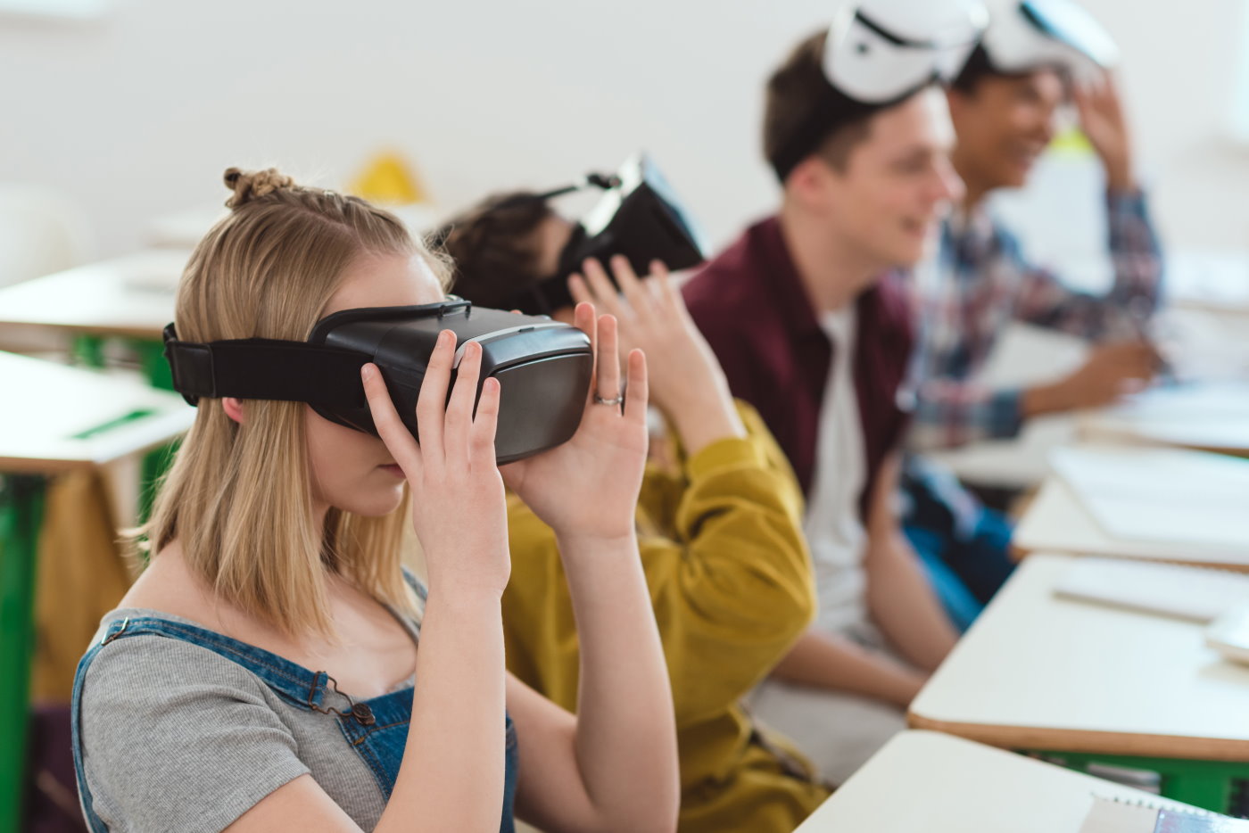 Side view of high school students taking off virtual reality headsets